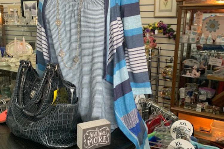 Display rack showcasing artwork and our talented Volunteers who merchandise at our Thrift